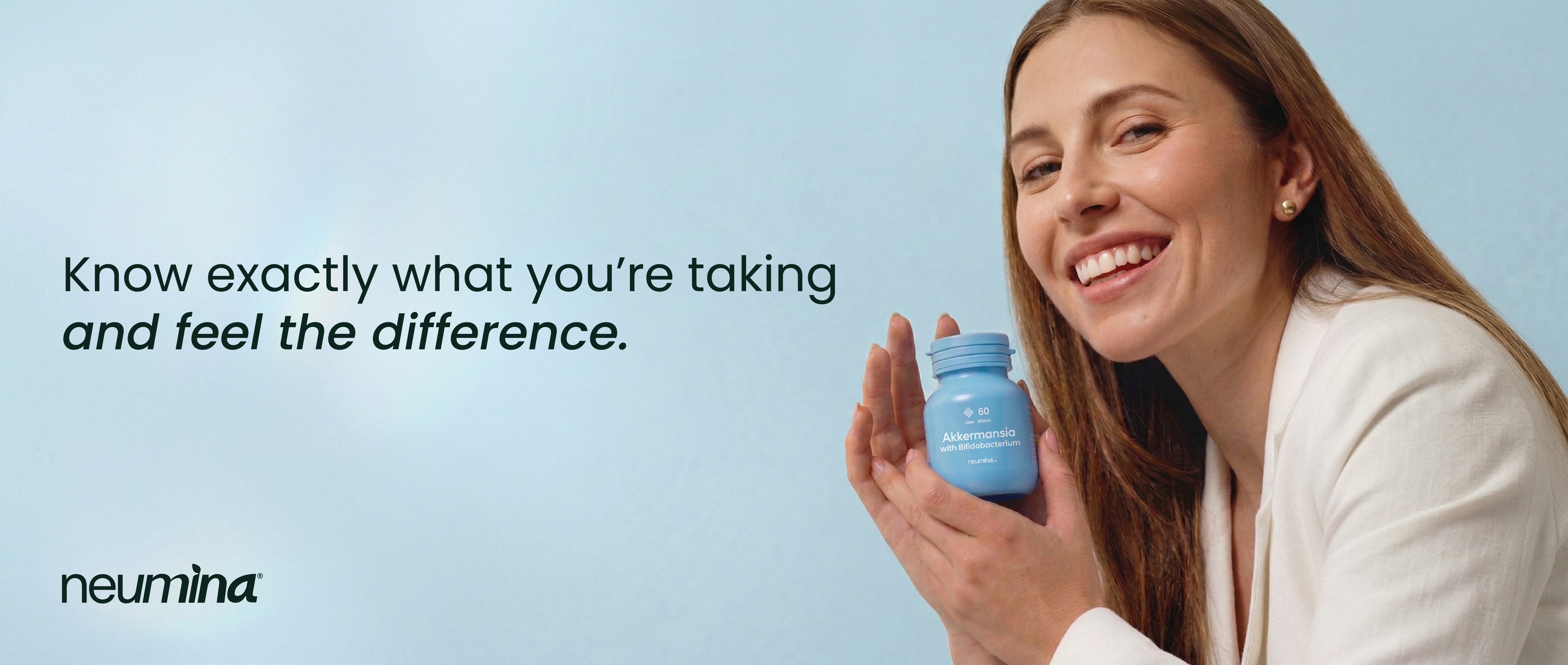 Neumina smiling woman holding probiotic supplement bottle - transparent ingredients and science-backed wellness brand