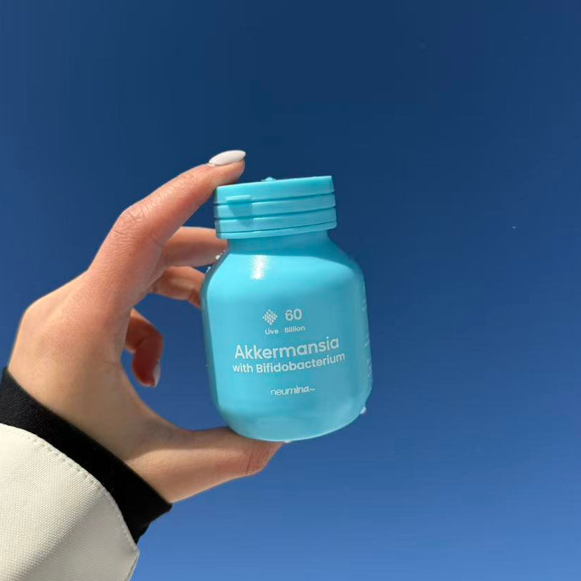 Neumina hand holding Akkermansia Bifidobacterium probiotic supplement outdoors for gut health and metabolic balance