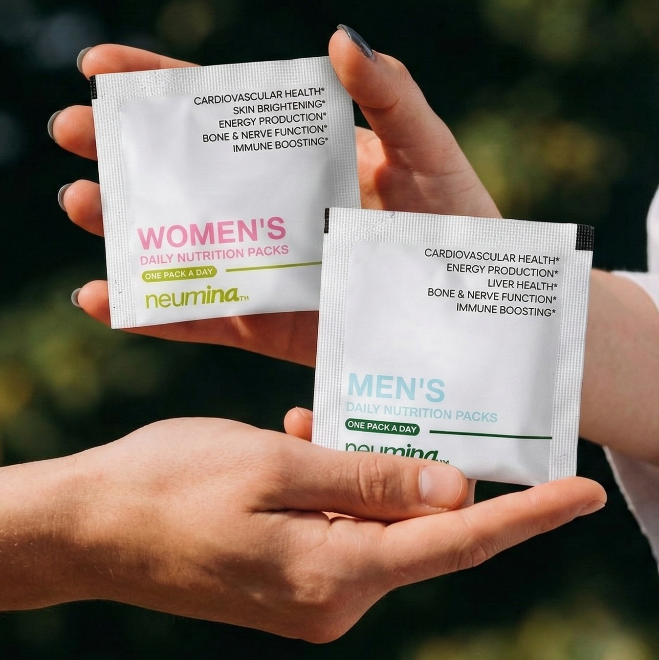 Neumina hands holding Men's and Women's daily nutrition packs - gender-specific precision wellness formulas